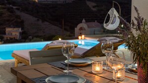 A dining table set for two with wine glasses, candles, and a vase of flowers.