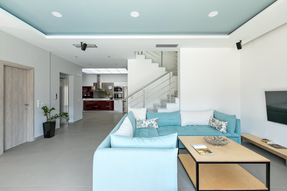 A modern living room with a light blue sofa, a coffee table, and a staircase leading to an upper level.