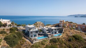 A modern villa with a pool, overlooking a coastal landscape.