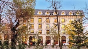 Un edificio grande de varios pisos con un estilo arquitectónico clásico, que cuenta con numerosas ventanas y una fachada simétrica.