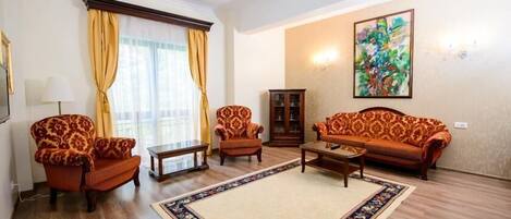 A living room with a sofa, two armchairs, a coffee table, and a cabinet.