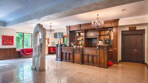 Un vestíbulo con mostrador de recepción, una araña de cristal, zona de espera y señalización de spa.