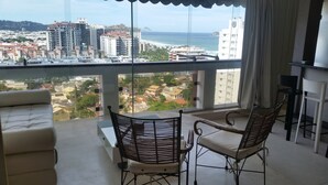 Un balcón con vistas a la ciudad y al mar. Hay un sofá y dos sillones.