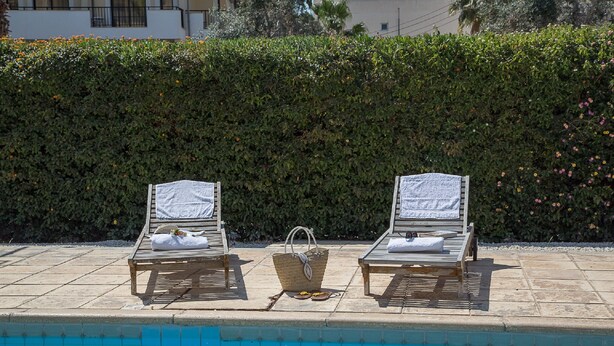 Two sun loungers with towels, a wicker basket, and a poolside setting. - Paphos Love Nest Apartment (Paphos)