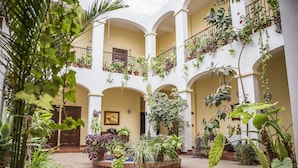 A spacious courtyard with multiple balconies, potted plants, and a central fountain. - Hospedium Hotel Val de Pinares (Bogarra)