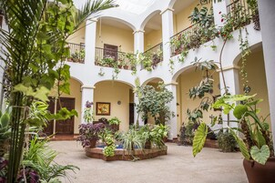 Un patio amplio con varios balcones, plantas en macetas y una fuente central.