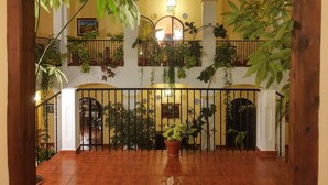 A spacious indoor area with a wooden staircase, potted plants, and a decorative railing. - Hospedium Hotel Val de Pinares (Bogarra)