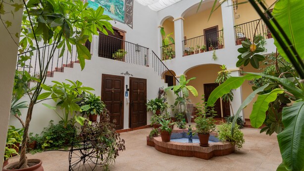 A spacious courtyard with multiple levels, potted plants, and a central fountain. - Hospedium Hotel Val de Pinares (Bogarra)