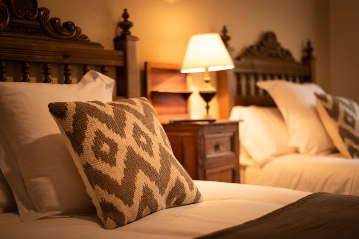 Une chambre d’hôtel avec un lit, des oreillers, une table de chevet et une lampe.