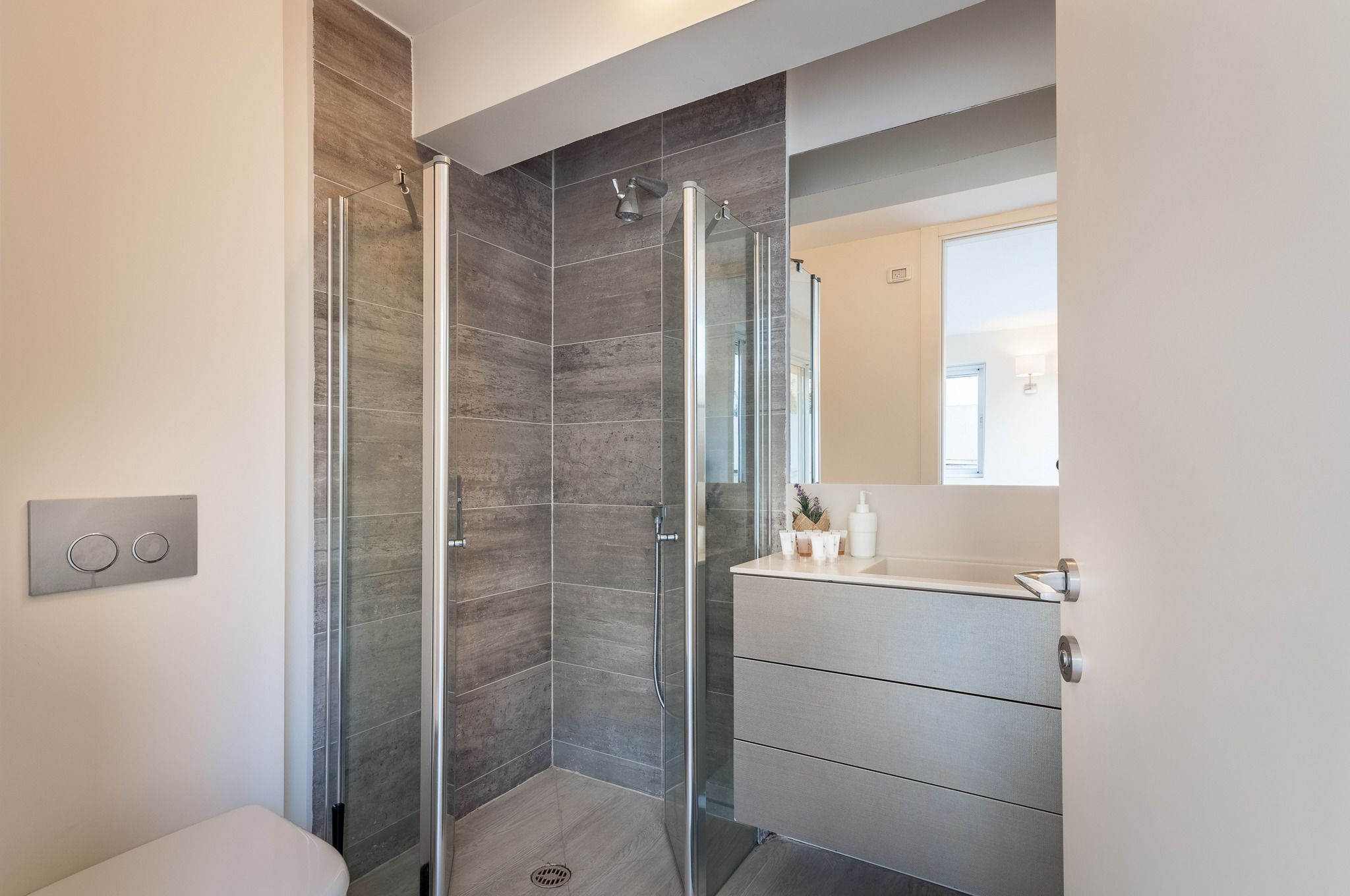 A modern bathroom with a glass shower enclosure, a white toilet, and a vanity with a mirror.