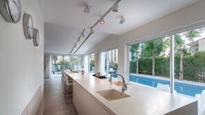 A modern kitchen with a large island, a built-in sink, and a view of a swimming pool. - Magical Villa in Herzliya (Herzliya)