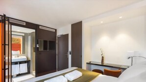 A modern hotel room with a bed, a bathroom, a desk, and a TV. - Hôtel Scarlett (Paris)