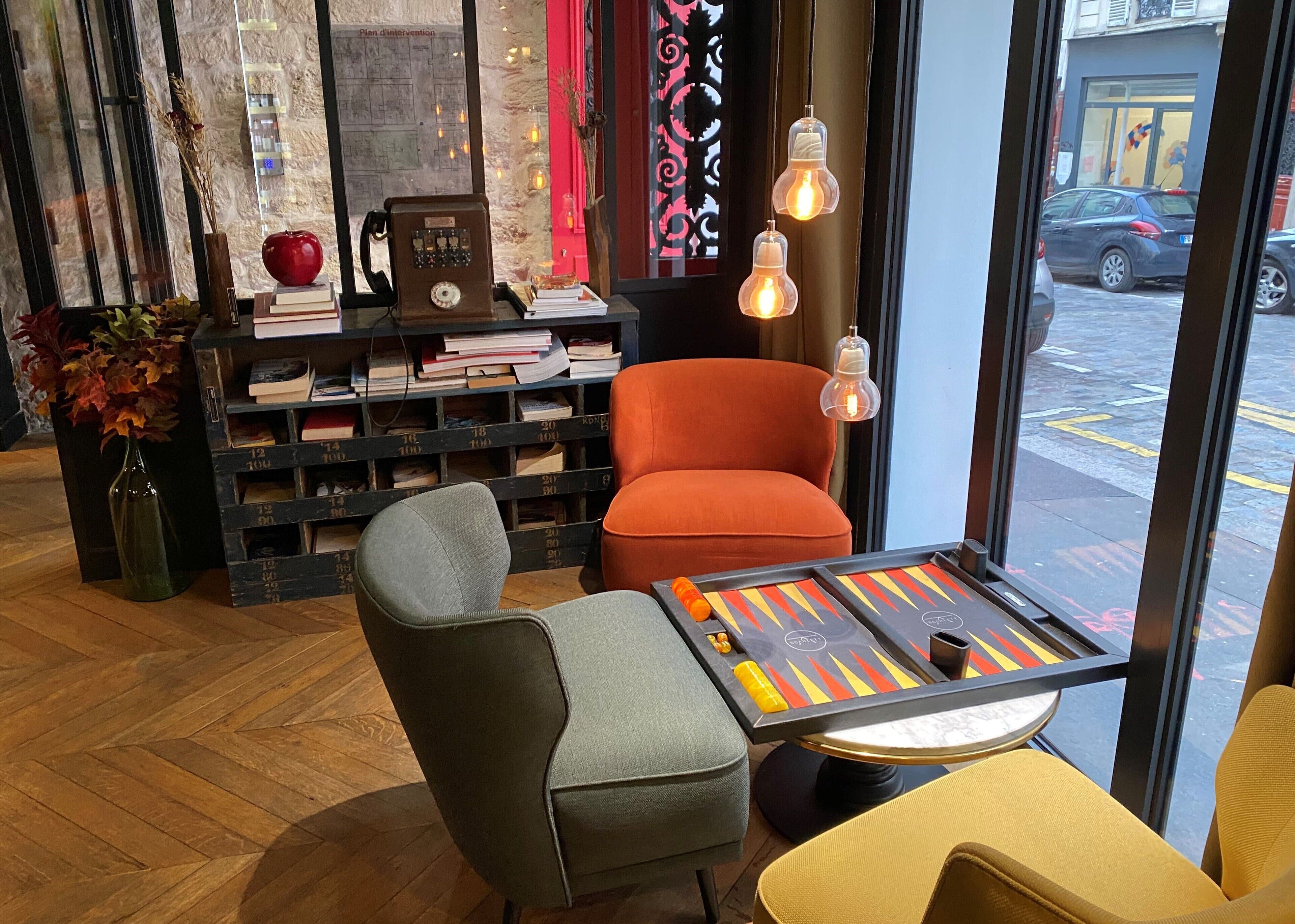 A cozy seating area with a table, a bookshelf, and a view of the street outside.
