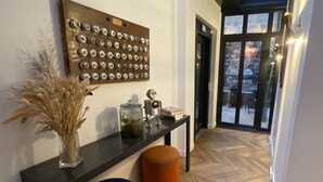 Et moderne interiør med en træmonteret udstilling, et glasgefælde, en lille robotfigur og en blå fodskammel.