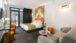 A hotel room with a bed, a sofa, a coffee table, and a desk with a lamp. - Hôtel Scarlett (Paris)