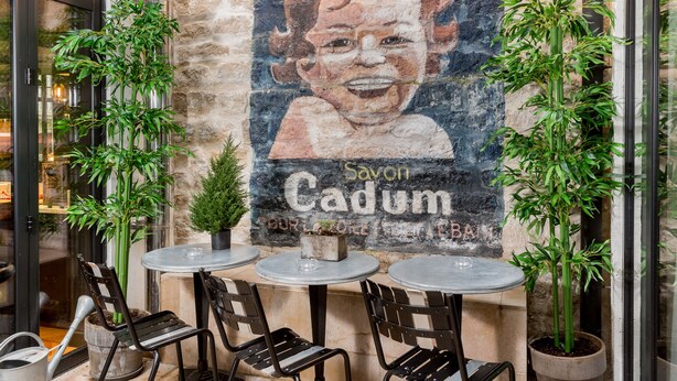 En café med udeservering, et vægmaleri og plantekasser.