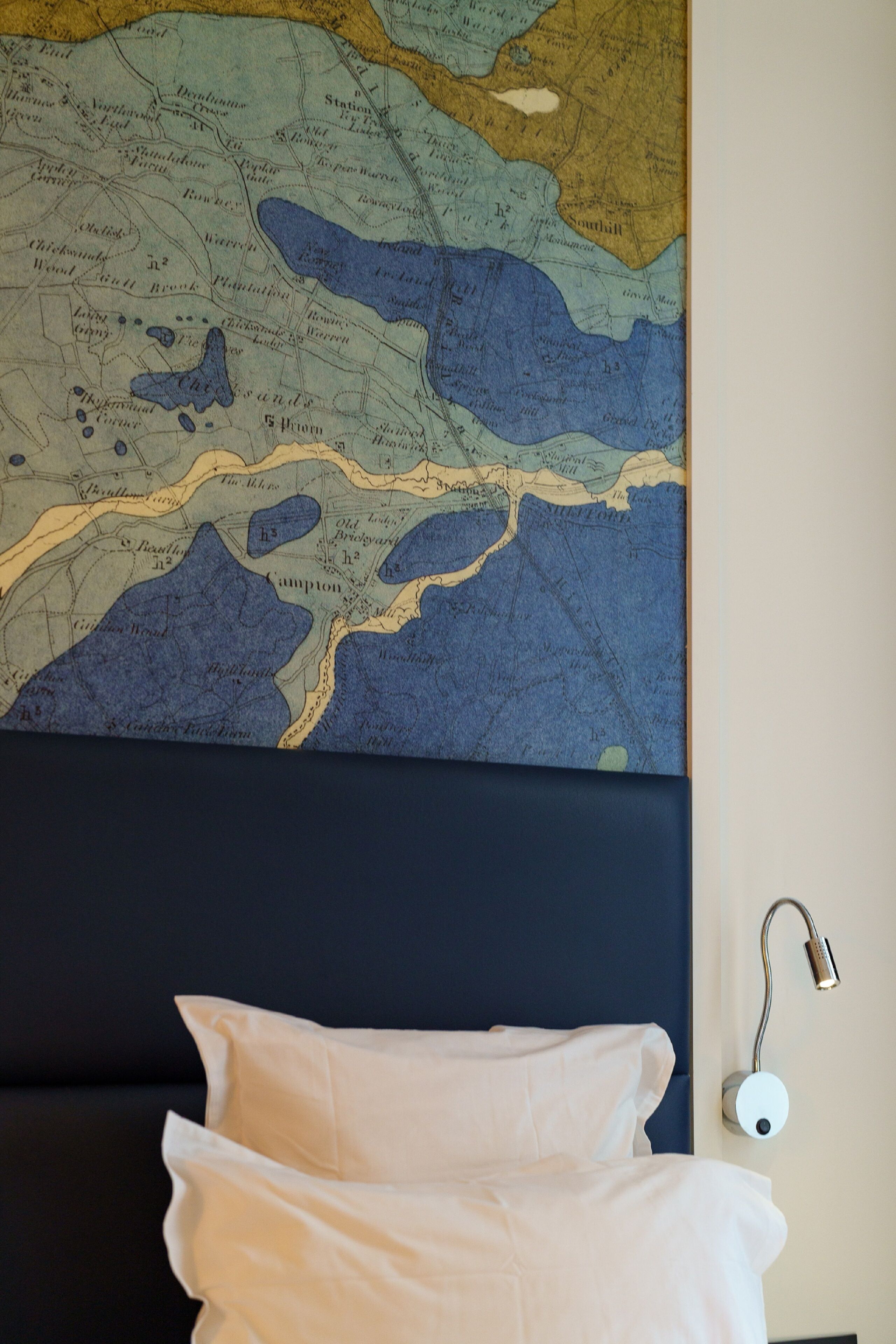 A bed with white bedding, a headboard, and a wall-mounted nightlight.