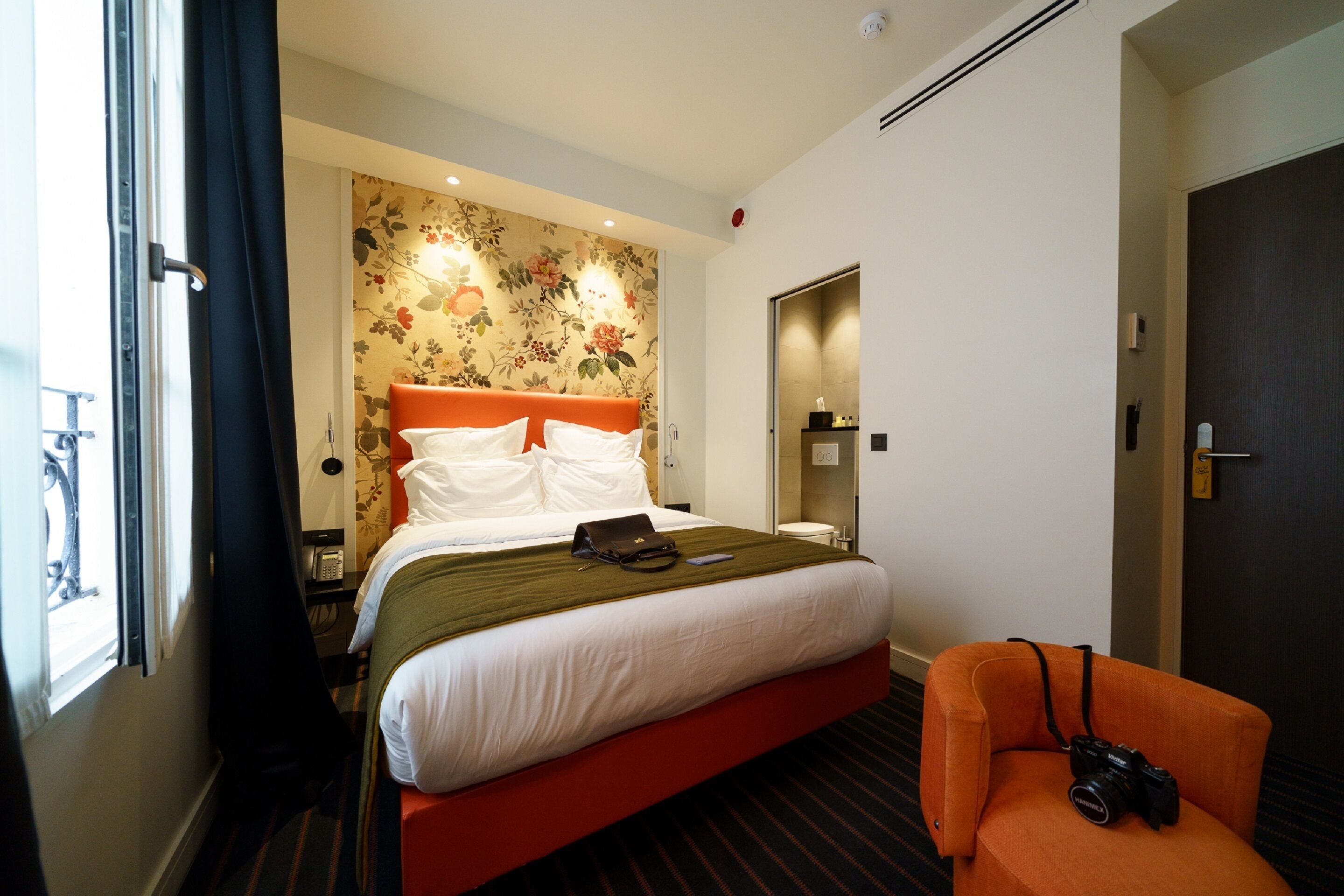 Una habitación de hotel con una cama, una silla, una ventana y una puerta.