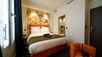 Una habitación de hotel con una cama, una silla, una ventana y una puerta.