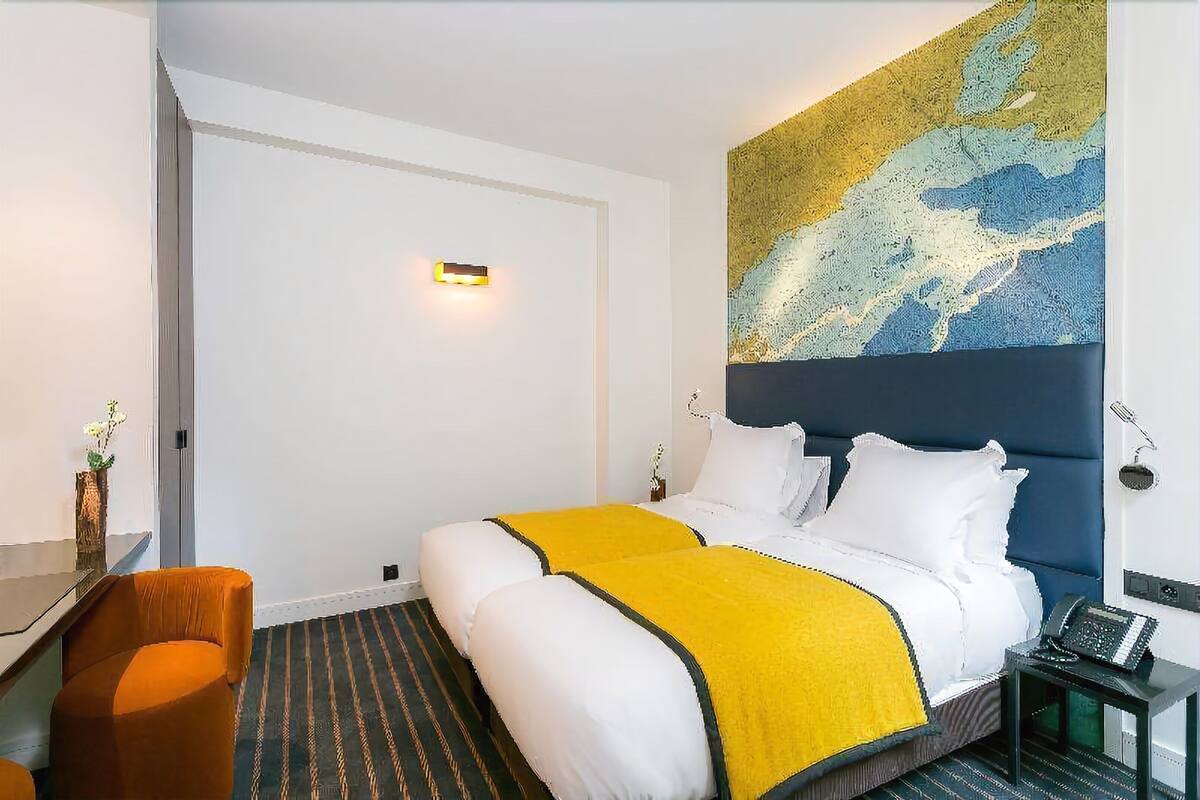 A hotel room with a bed, a desk, and a chair.
