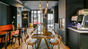 A modern dining area with a long table, chairs, and pendant lighting. - Hôtel Scarlett (Paris)