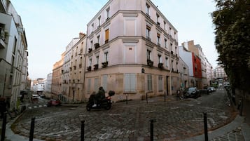 Un edificio histórico con fachada de esquina, calle adoquinada y una motocicleta pasando.