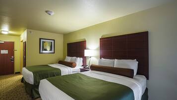 Habitación de hotel con dos camas, un cuadro enmarcado en la pared y una puerta con un letrero.