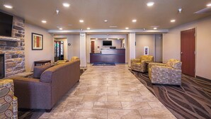 A lobby with a reception desk, sofas, a fireplace, and a patterned carpet. - Cobblestone Inn & Suites - Altamont (Altamont)