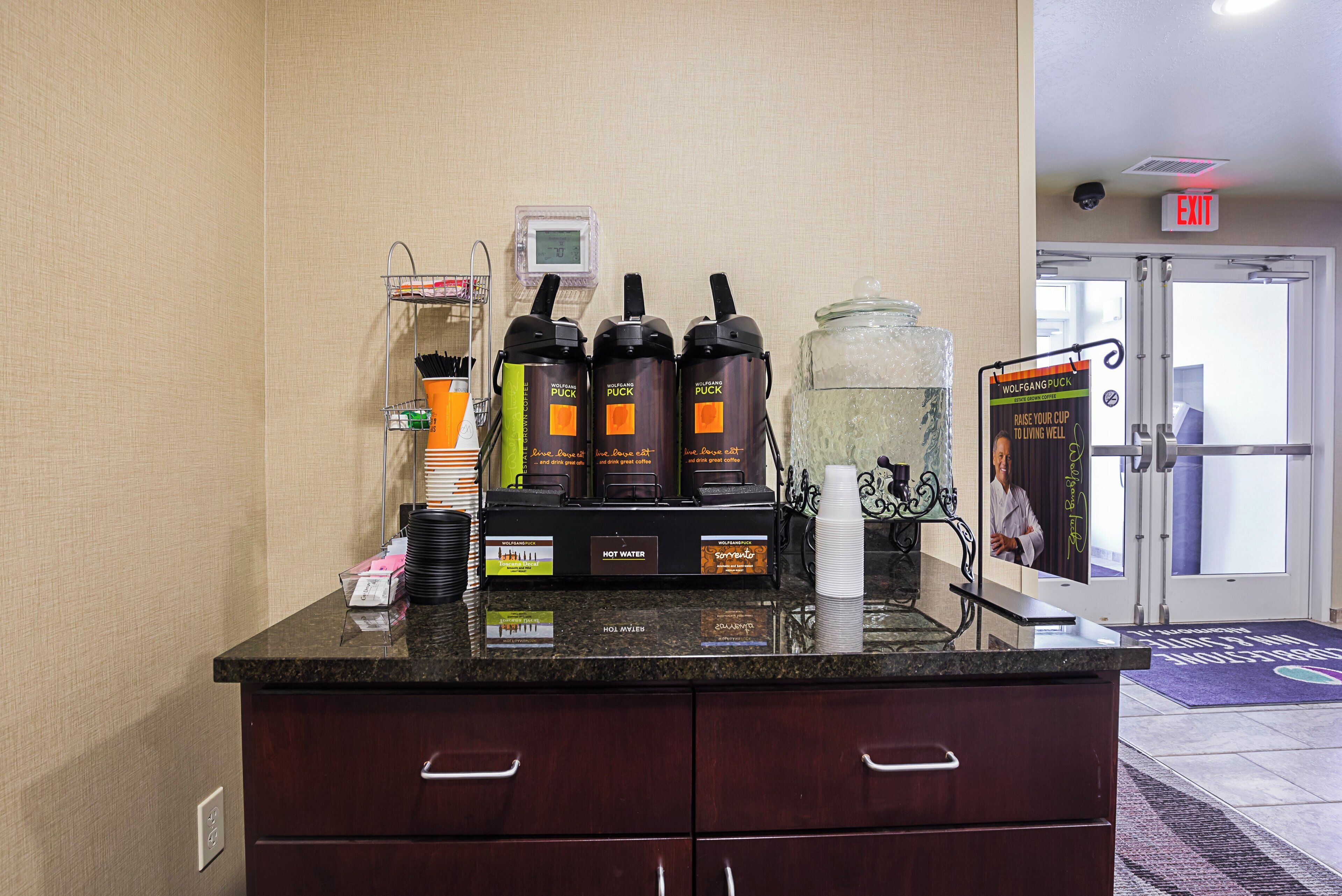 A hotel reception area with a coffee station, a digital clock, and a glass container.