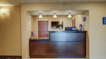 A reception desk with a flat-screen TV, a digital kiosk, and a wooden door.