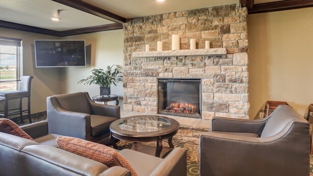A cozy living room with a stone fireplace, leather sofas, and a flat-screen TV. - Cobblestone Inn & Suites - Altamont (Altamont)