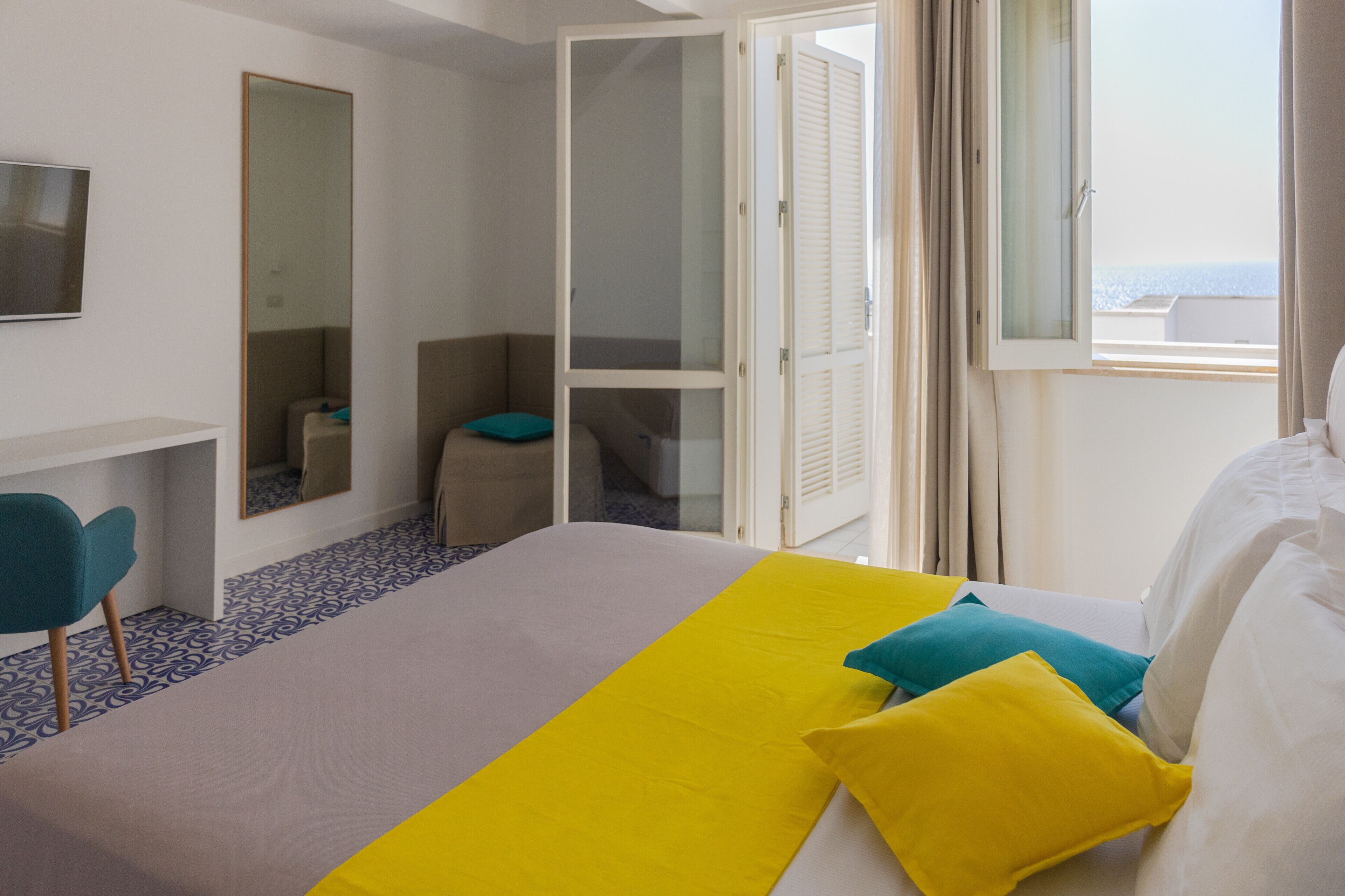 A hotel room with a bed, a desk, a chair, and a large window with a view.