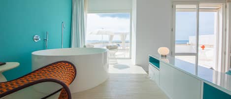 Un baño moderno con bañera, ducha y vistas a la playa.