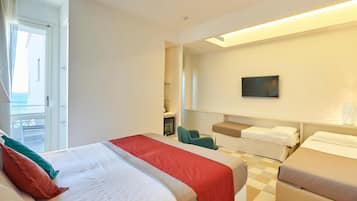 Una habitación de hotel con una cama grande, una cama más pequeña, un escritorio, una silla y un televisor.