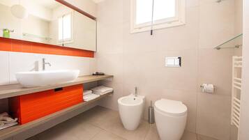 Un baño moderno con un lavamanos grande de color blanco, un bidé y un inodoro.