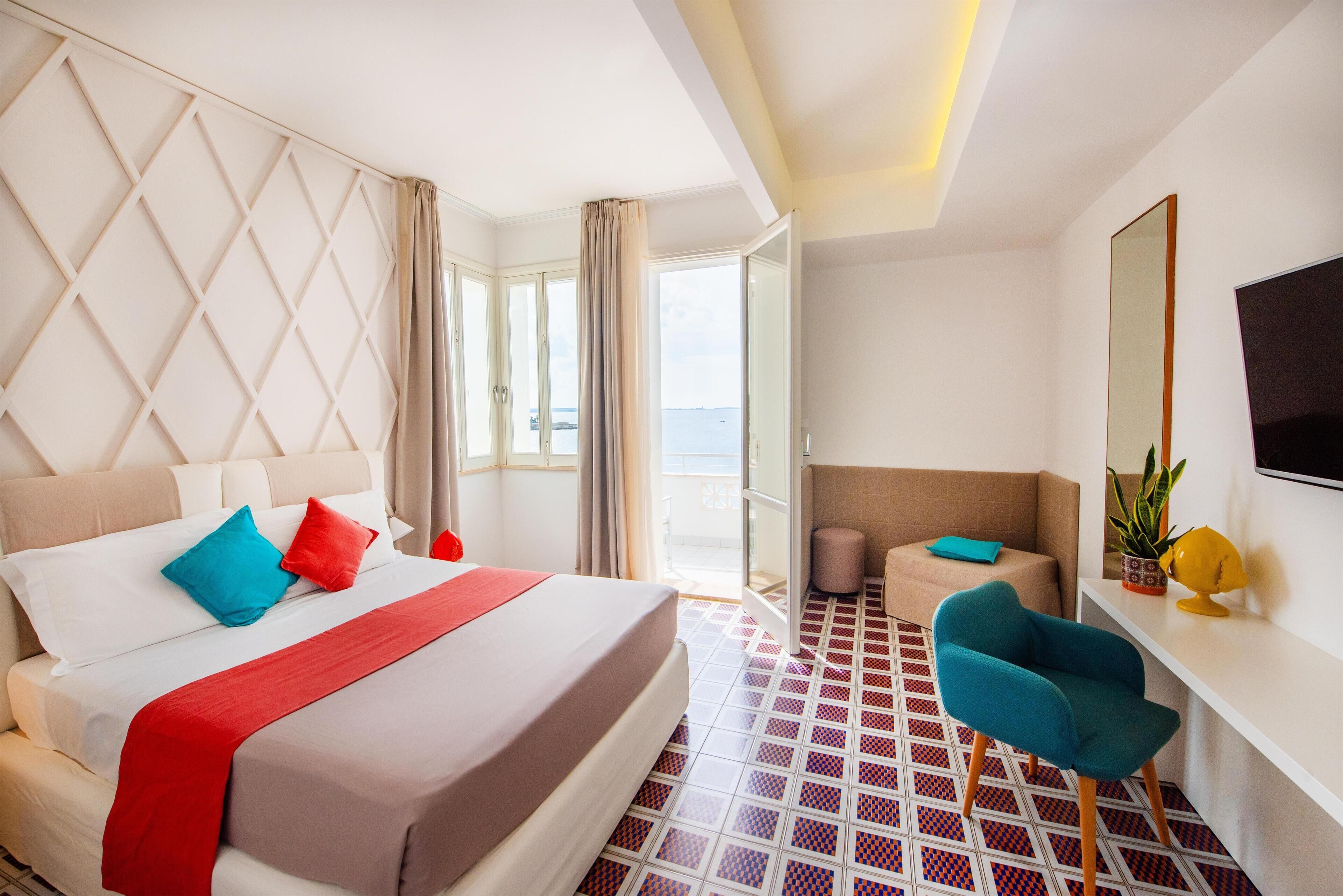 Habitación de hotel con cama, escritorio, silla y ventana grande con vistas.