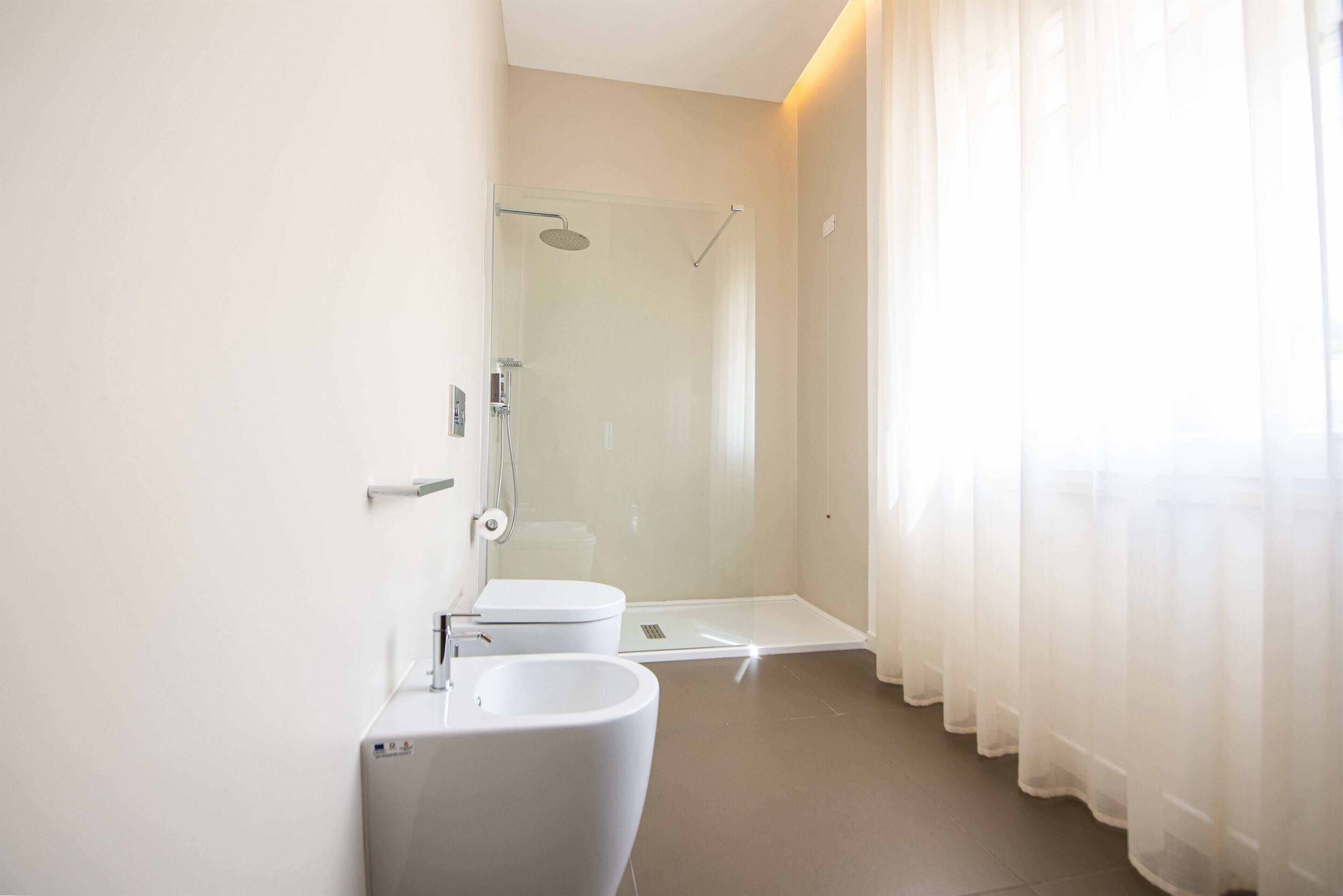 A modern bathroom with a glass shower enclosure, a toilet, and a sink.
