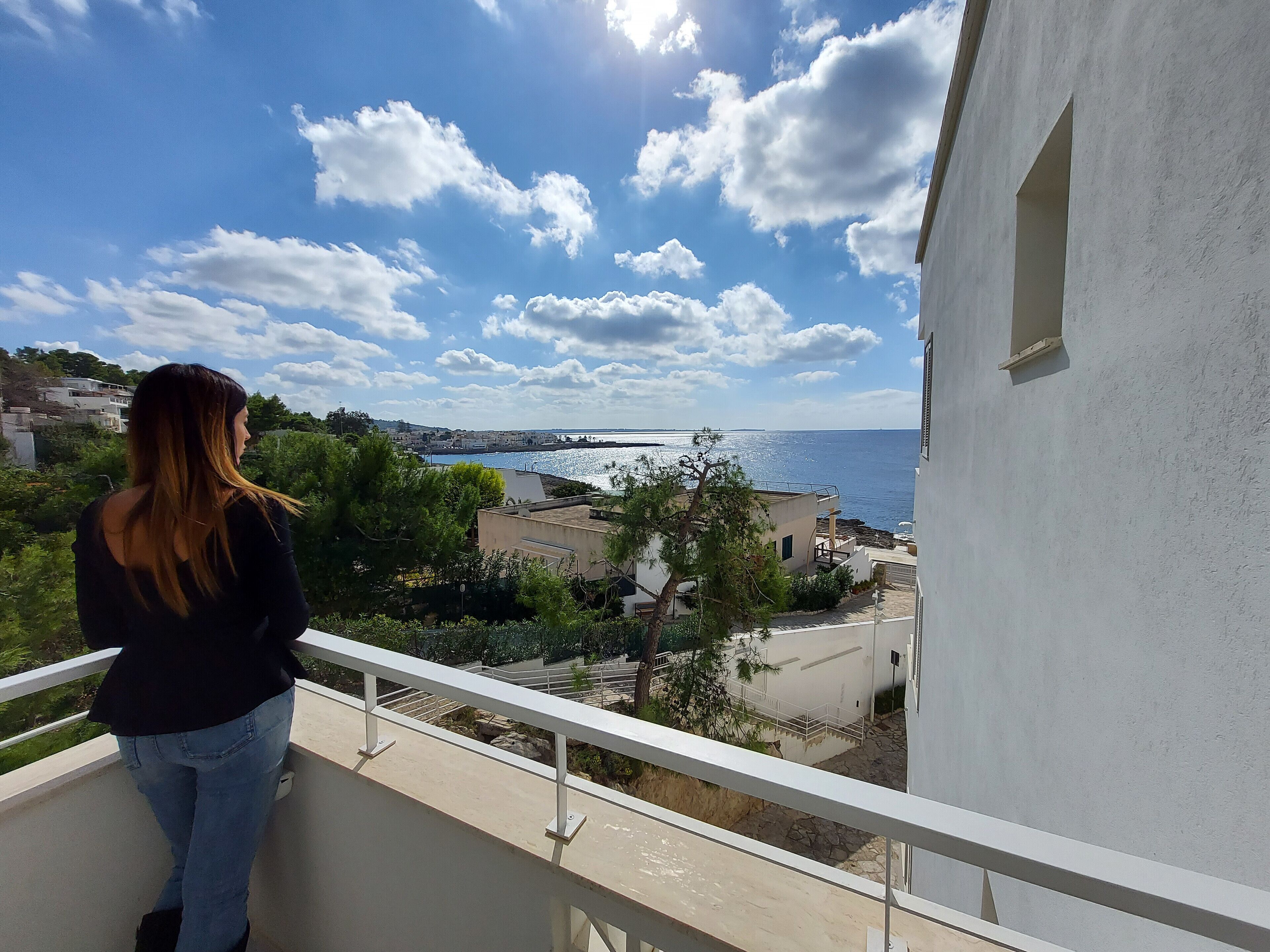 Un balcón con vistas a un pueblo costero, cielo despejado y mar.