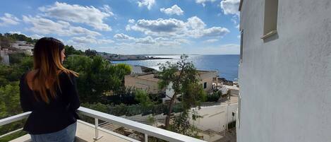 Un balcón con vistas a un pueblo costero, cielo despejado y mar.