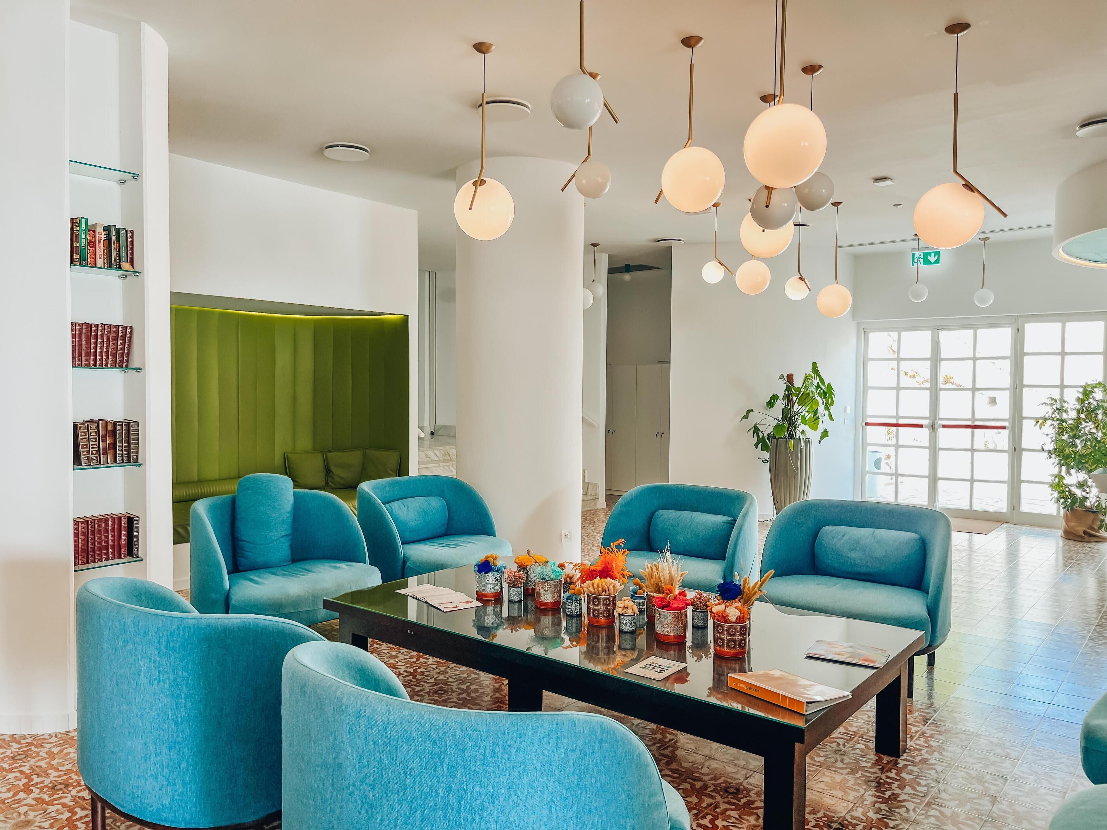 Una sala moderna con sillas color esmeralda, una mesa de centro de vidrio y una pared de acento verde.