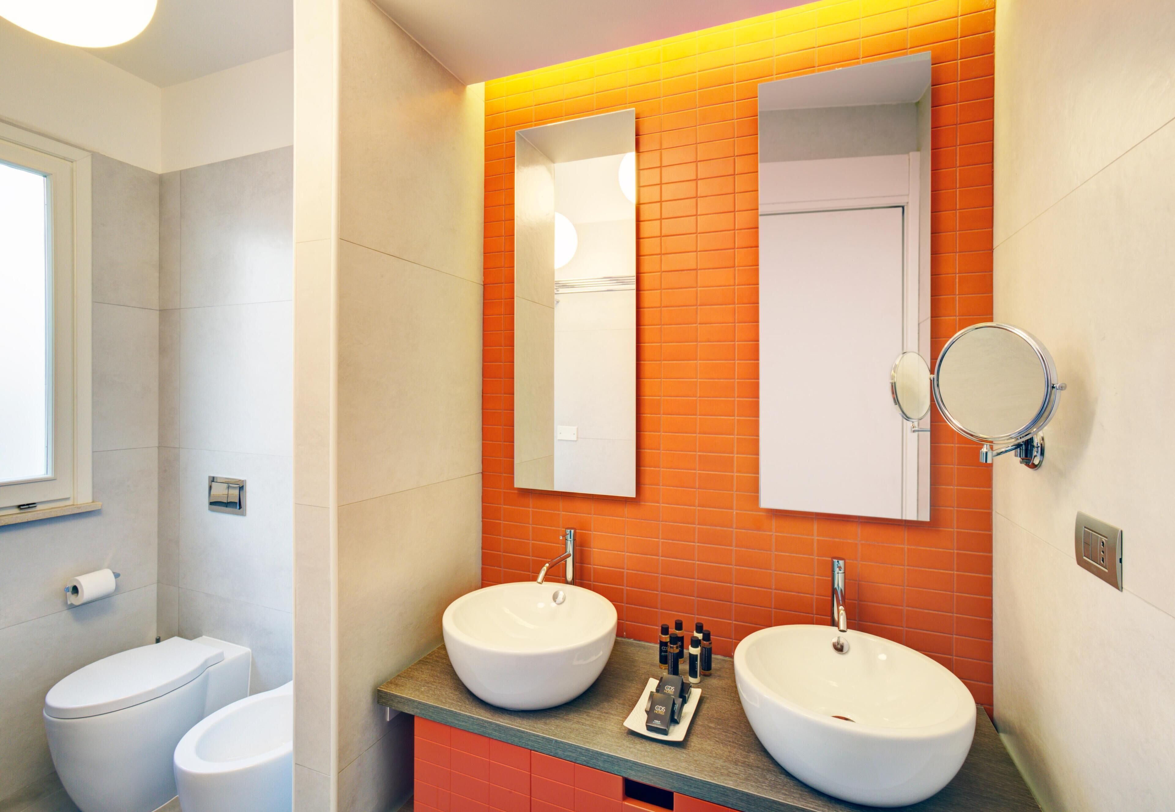 A modern bathroom with two sinks, a toilet, and a mirror.