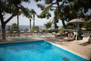 Una piscina al aire libre de temporada, sombrillas