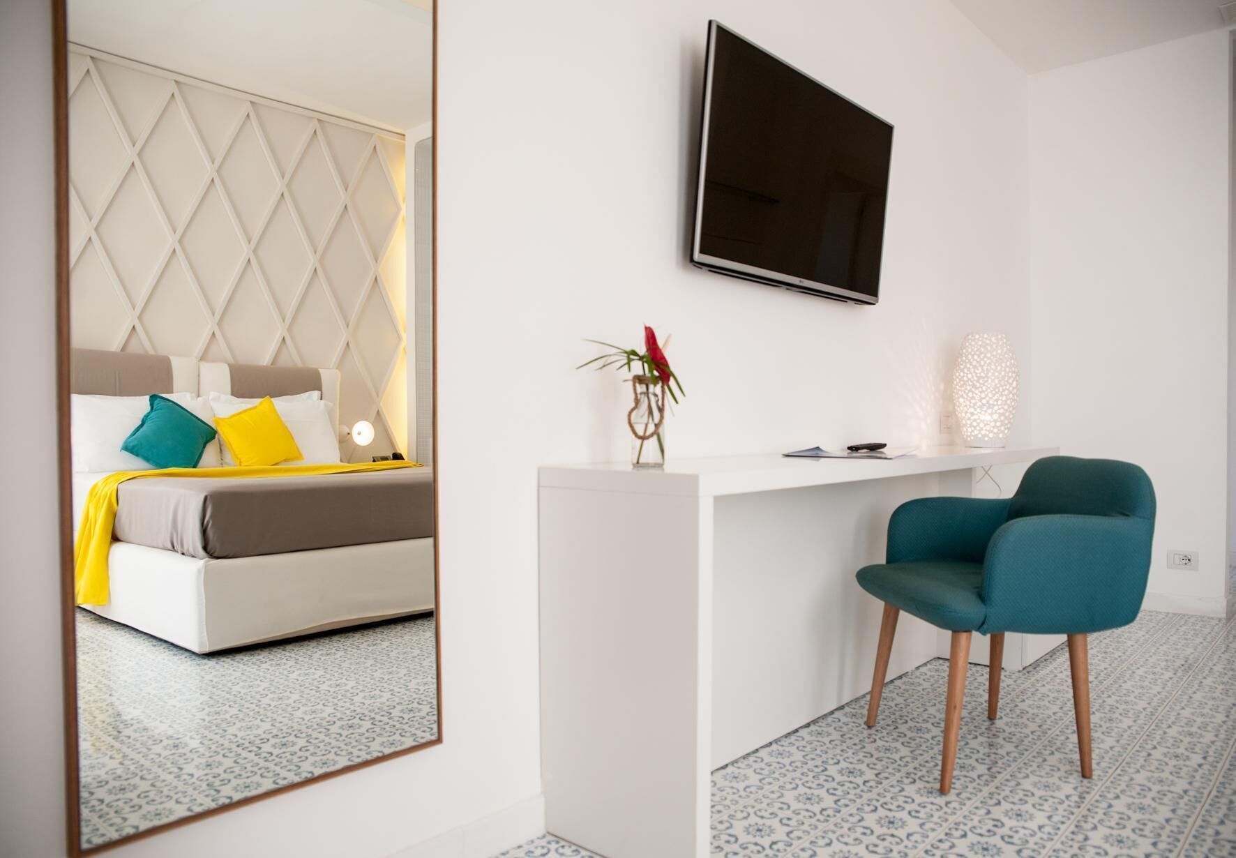 Une chambre d’hôtel moderne équipée d’un lit, d’un bureau, d’une chaise, d’une télévision et d’un vase décoratif.