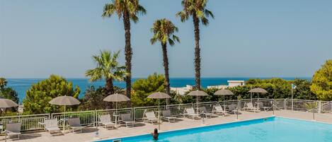 Una piscina al aire libre de temporada, sombrillas, tumbonas