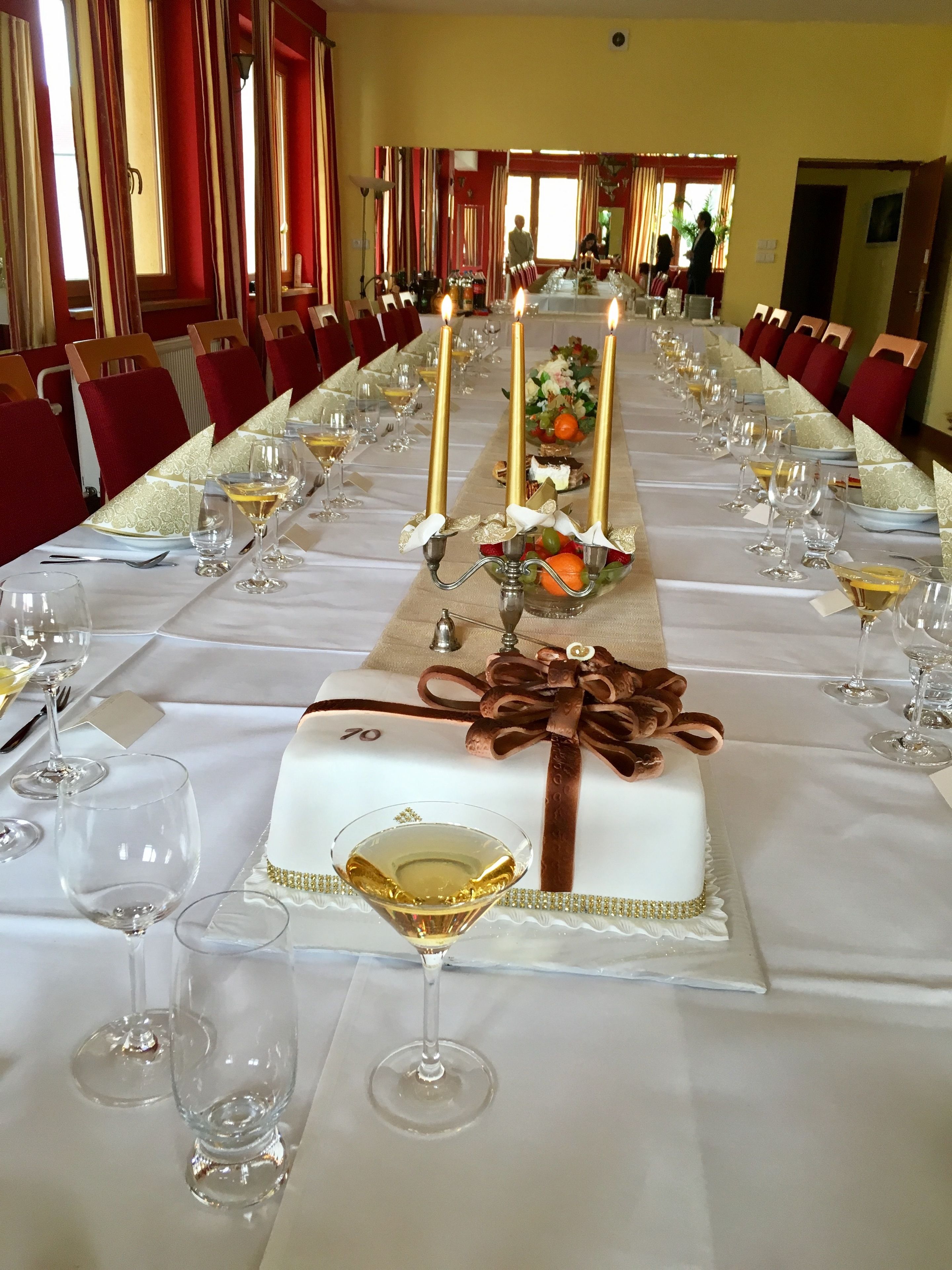 Une longue table de banquet, décorée de bougies, sur laquelle sont disposés un gâteau et des verres à vin.