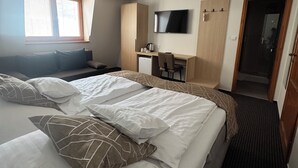 A hotel room with a large bed, a desk, a television, and a wardrobe. - Tavel Boutique Hotel (Prešov)