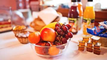 Een ontbijtbuffet met fruit, vruchtensappen en toevoegingen.