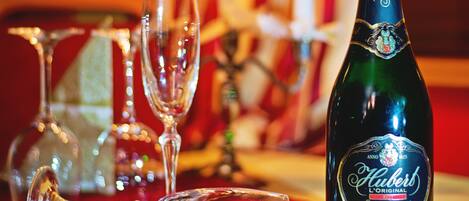 A bottle of champagne, two glasses, and a candle on a table with a red tablecloth.
