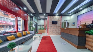 A modern lobby with a red carpet, a grey sofa with yellow cushions, a reception desk, and a brick wall. - Elite Marmara Hotel Gungoren (Istanbul)