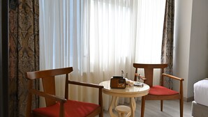 A hotel room with two wooden chairs with red cushions, a small round table with a radio, and a bed with white bedding. - Elite Marmara Hotel Gungoren (Istanbul)